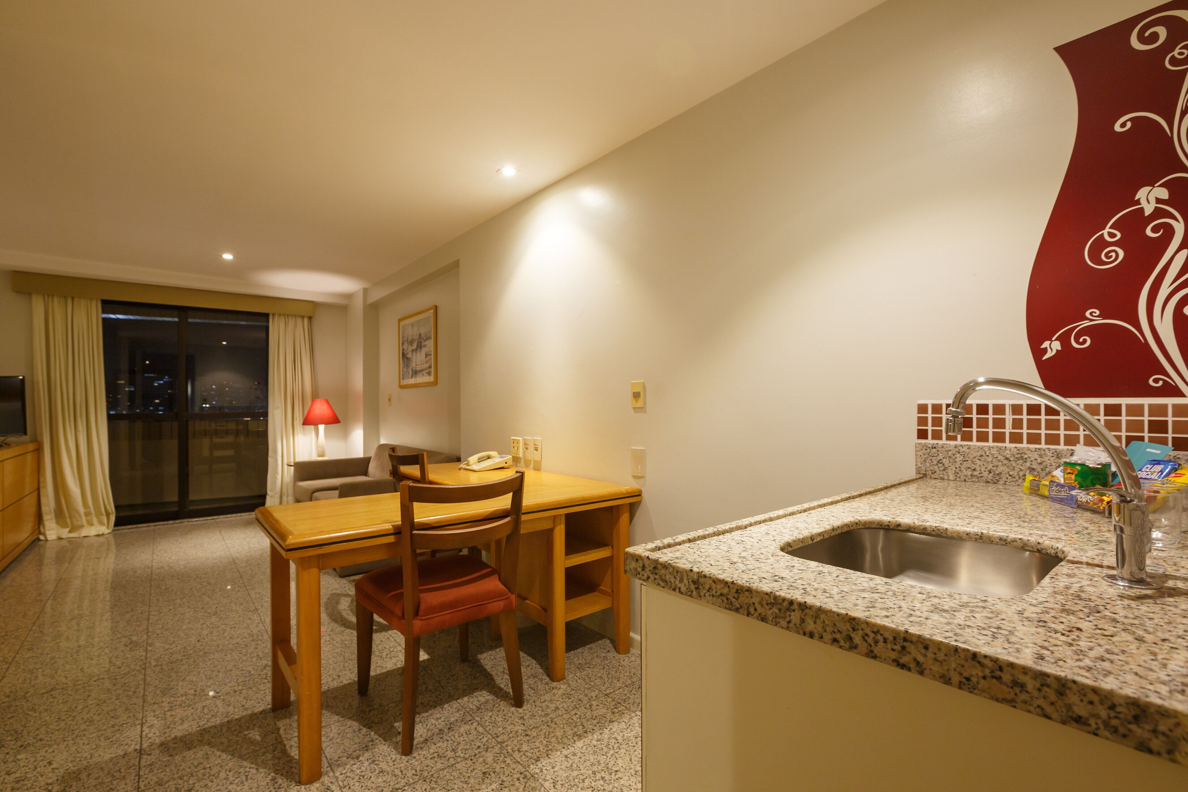 A compact kitchen with a granite countertop, a sink, and a dining area with a table and chairs.