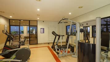 A gym with cardio machines, weight training equipment, and a large mirror.
