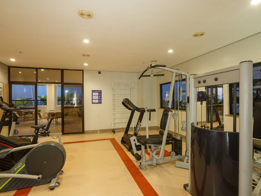 A gym with cardio machines, weight training equipment, and a large mirror.