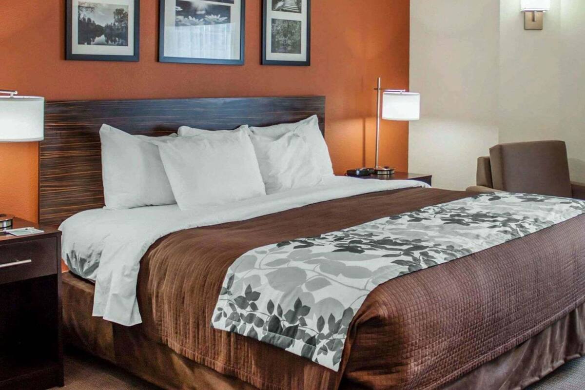 A hotel room with a bed, two bedside tables, a chair, and three framed pictures on the wall.