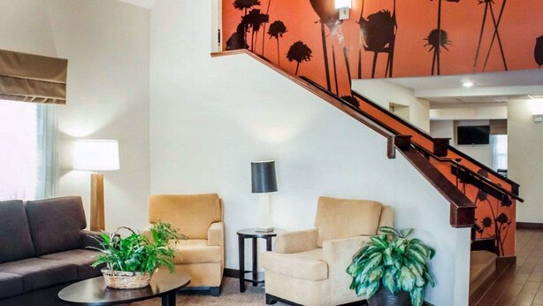 A living room with a sofa, two armchairs, a coffee table, and a potted plant. A staircase with a railing leads to an upper level. - Sleep Inn North Charleston Ashley Phosphate (North Charleston)