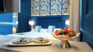 A hotel room with a bed, a bedside table with a fruit bowl, and a mirror.