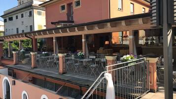 A rooftop terrace with outdoor seating, a staircase, and a view of adjacent buildings.