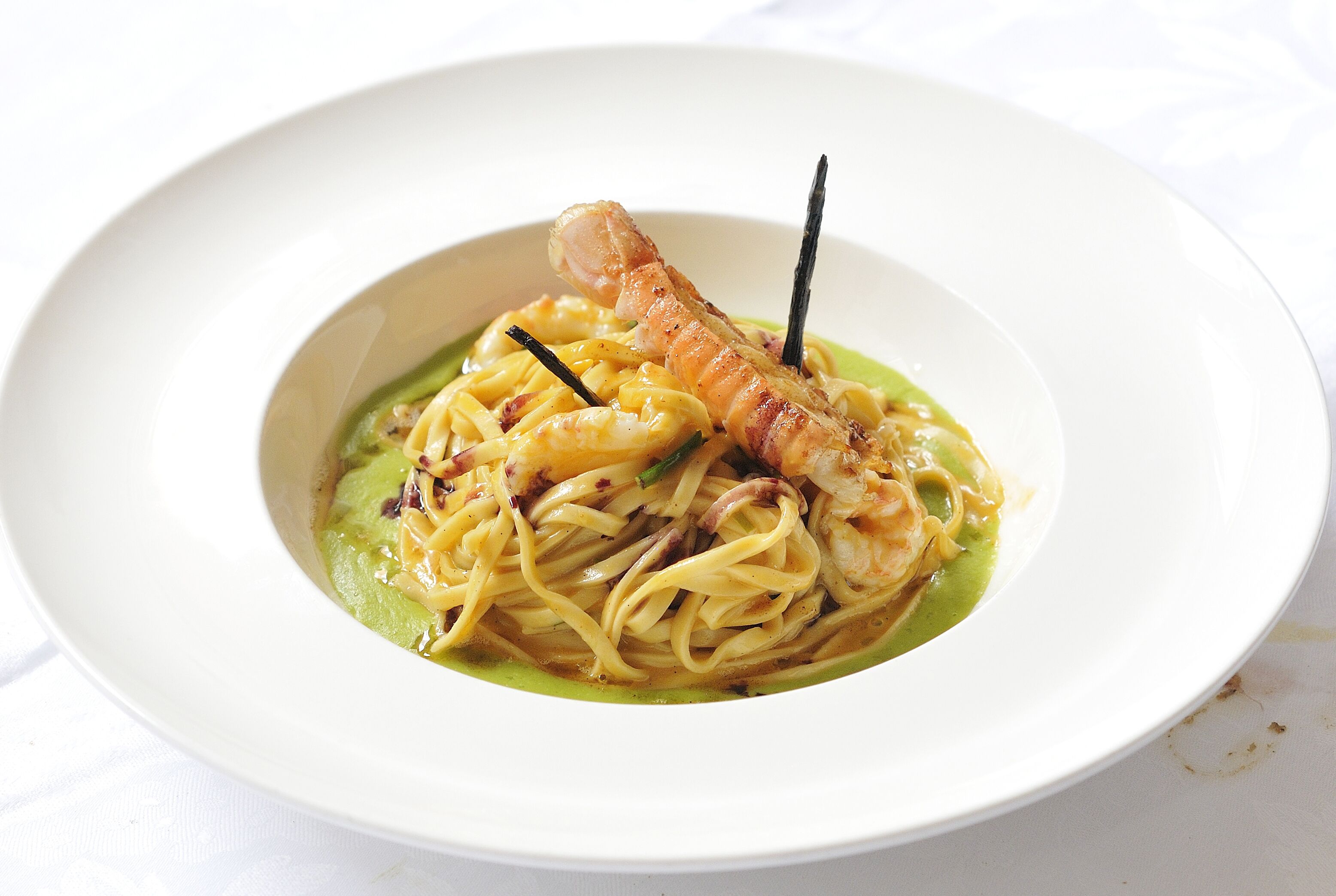 Ein Teller Pasta mit Garnelen und einer Dekoration.