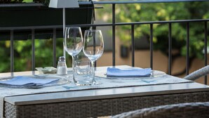 Une table en osier, placée à l’extérieur, sur laquelle se trouvent deux verres à vin, un salier et une serviette.