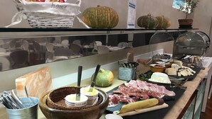 Un buffet proposant une variété de plats, notamment des viandes, des fromages et du pain.