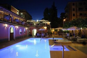 Una piscina al aire libre, sombrillas, sillones reclinables de piscina
