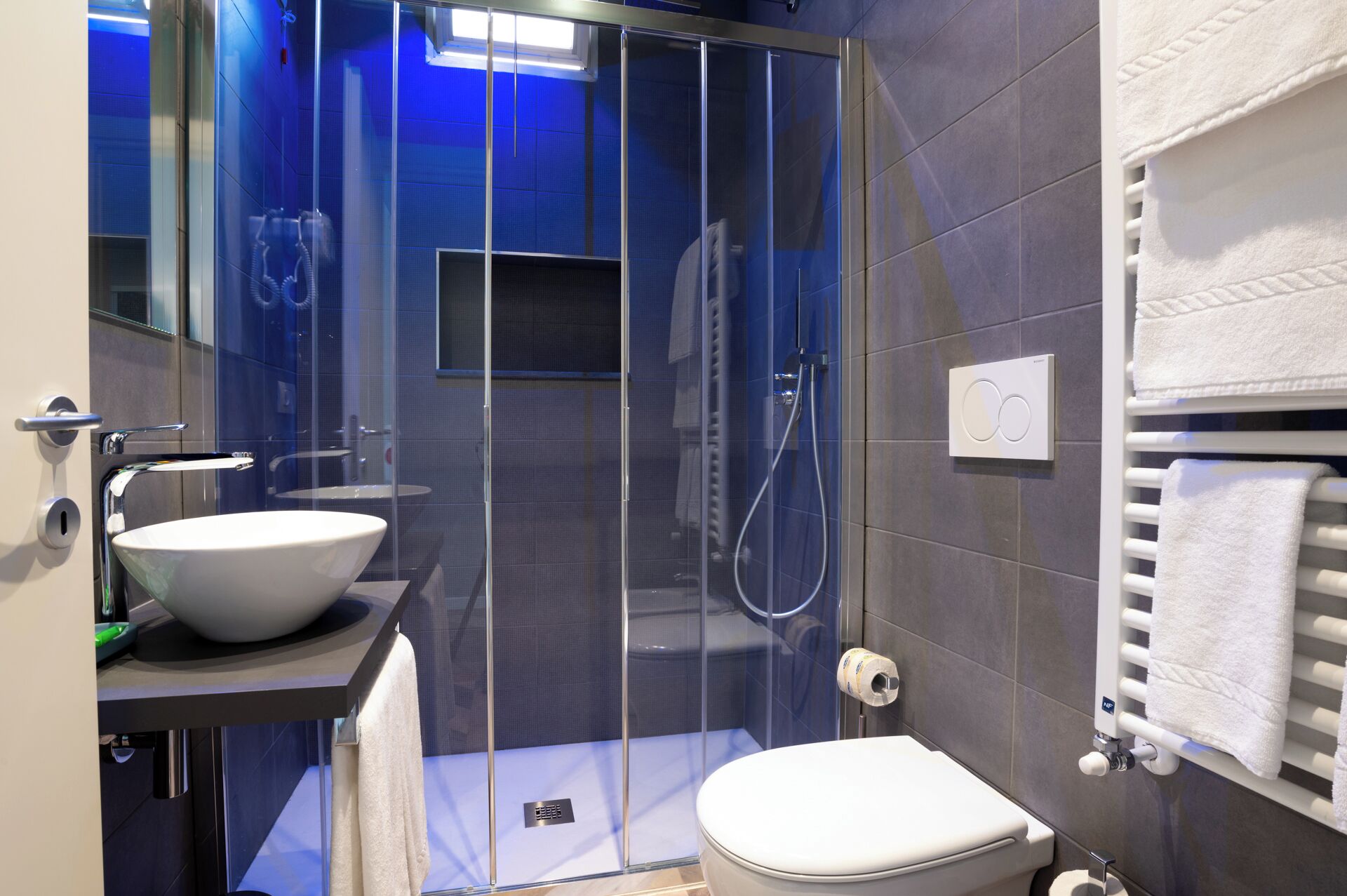 Un baño moderno con ducha de vidrio, lavamanos blanco y un inodoro.