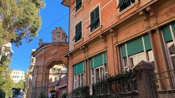 Un edificio histórico con un arco destacado, contraventanas verdes y un letrero que indica zona de no estacionamiento.