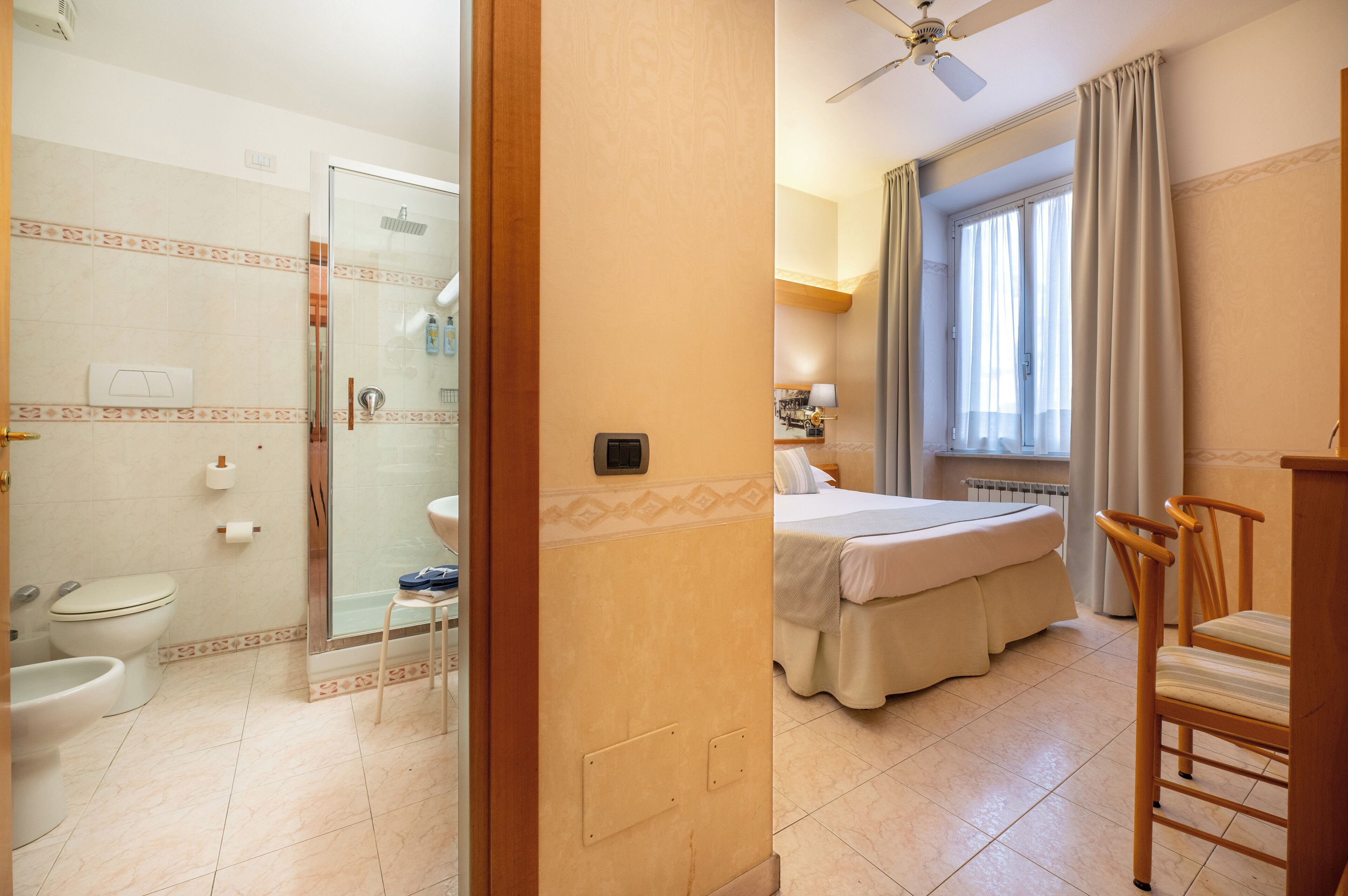 Hotellihuone, jossa on suihku, wc ja ikkunallinen sänky.