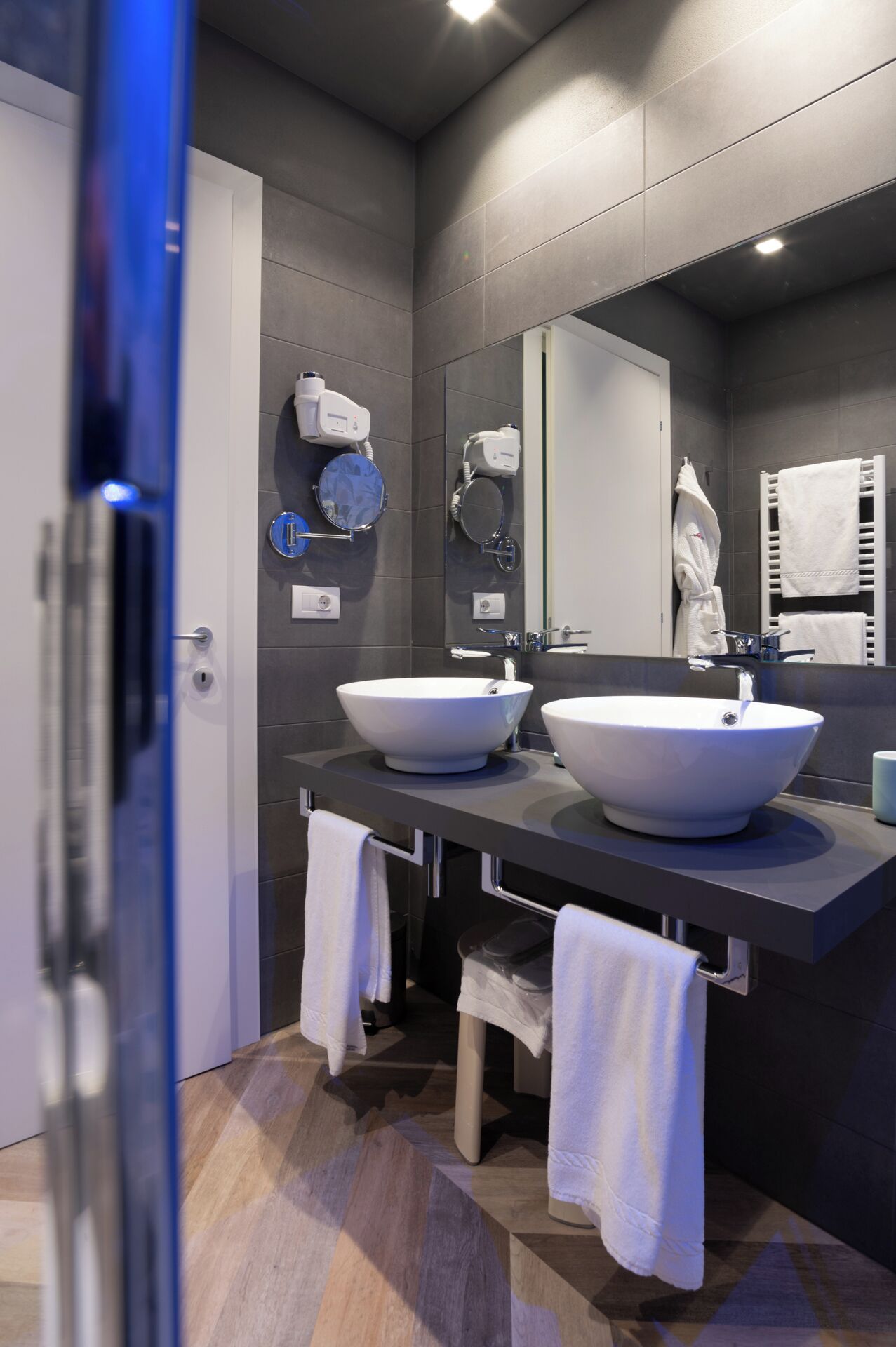 Un baño moderno con dos lavamanos, un espejo y un perchero para toallas.