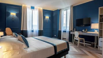 A hotel room with a large bed, a desk, a chair, a television, and a window with curtains.