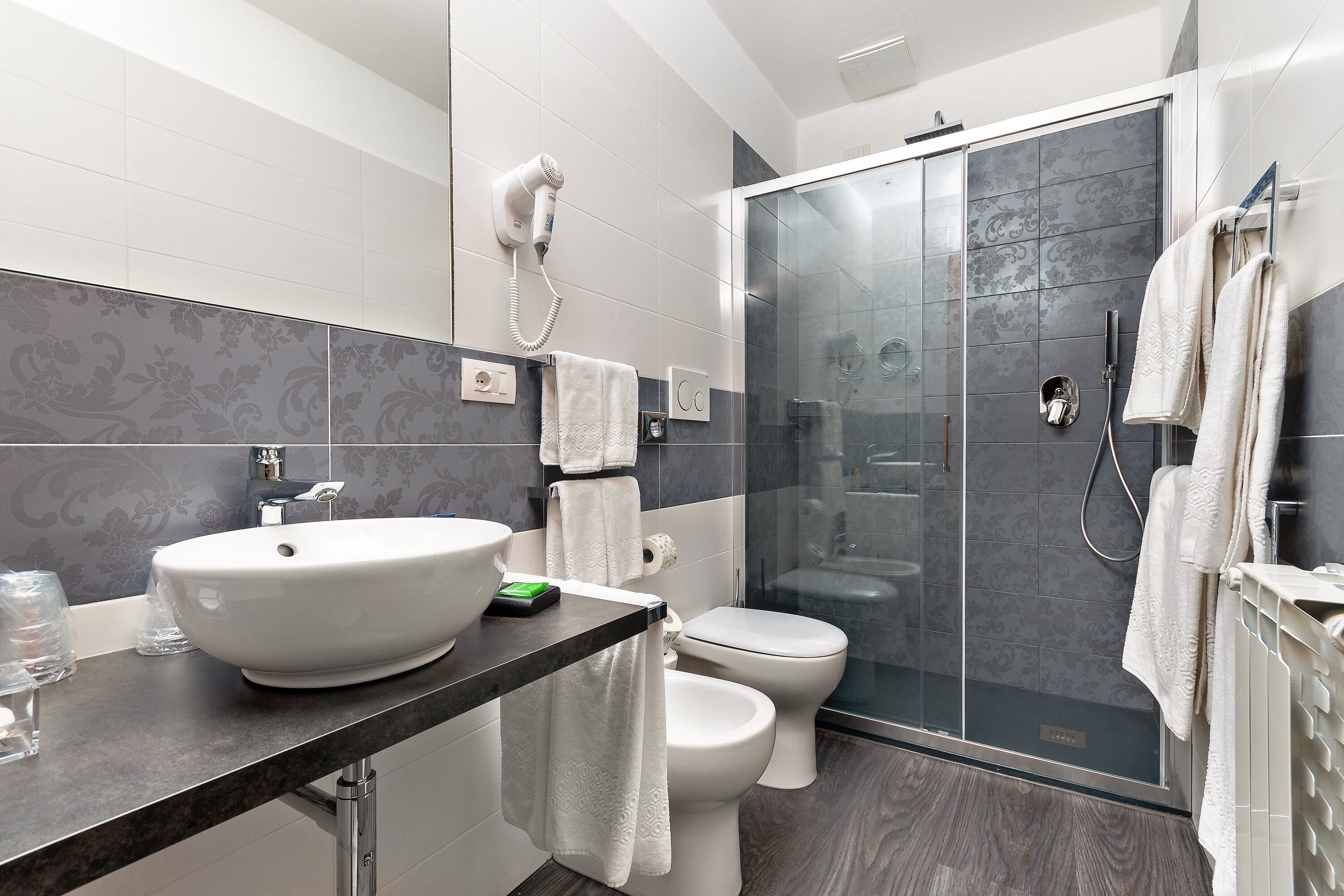 A modern bathroom with a large sink, toilet, and glass shower enclosure.