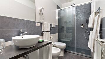 A modern bathroom with a large sink, toilet, and glass shower enclosure.