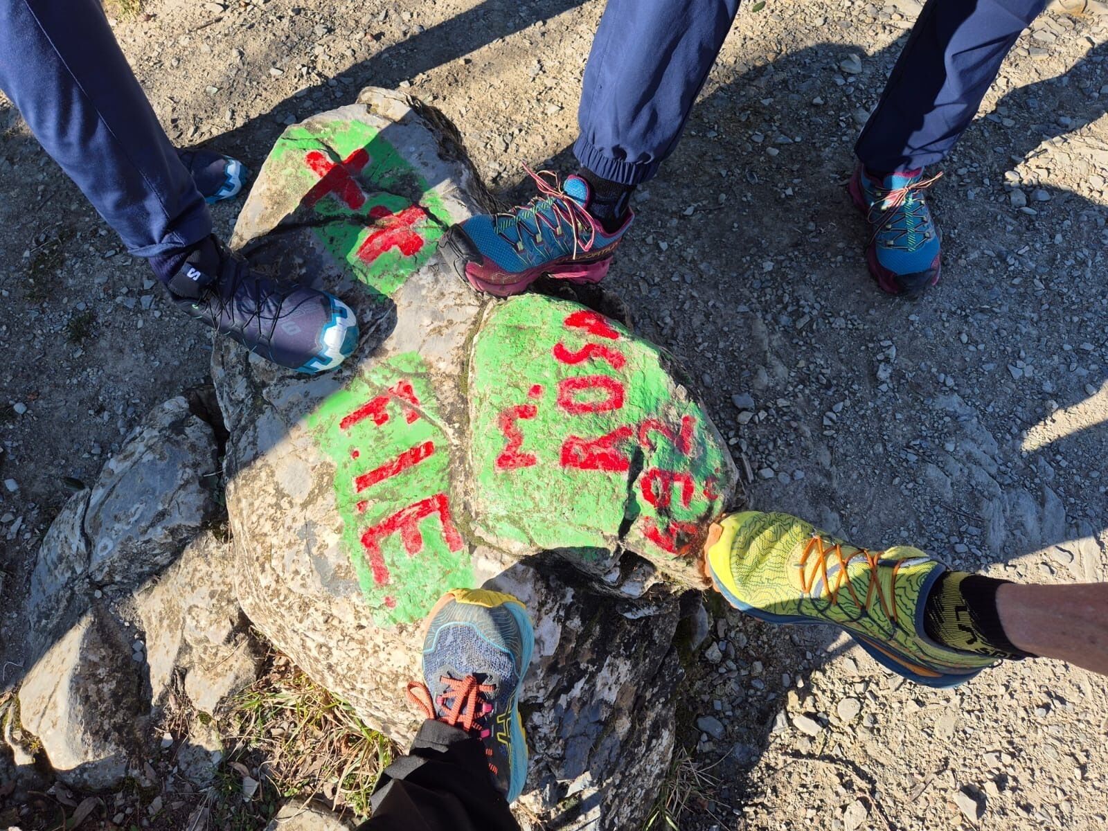 Un groupe de personnes se tient sur une surface rocheuse, et des lettres peintes sont visibles sur le sol.