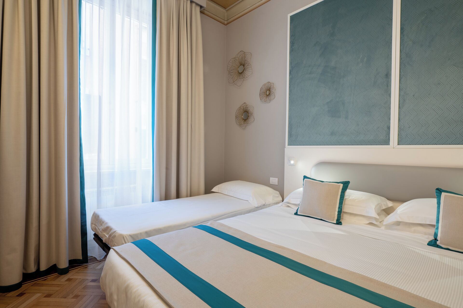 A hotel room with two beds, a large window with a view, and a patterned wall.