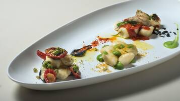 A white oval plate with a seafood dish, including shrimp, scallops, and a green sauce.