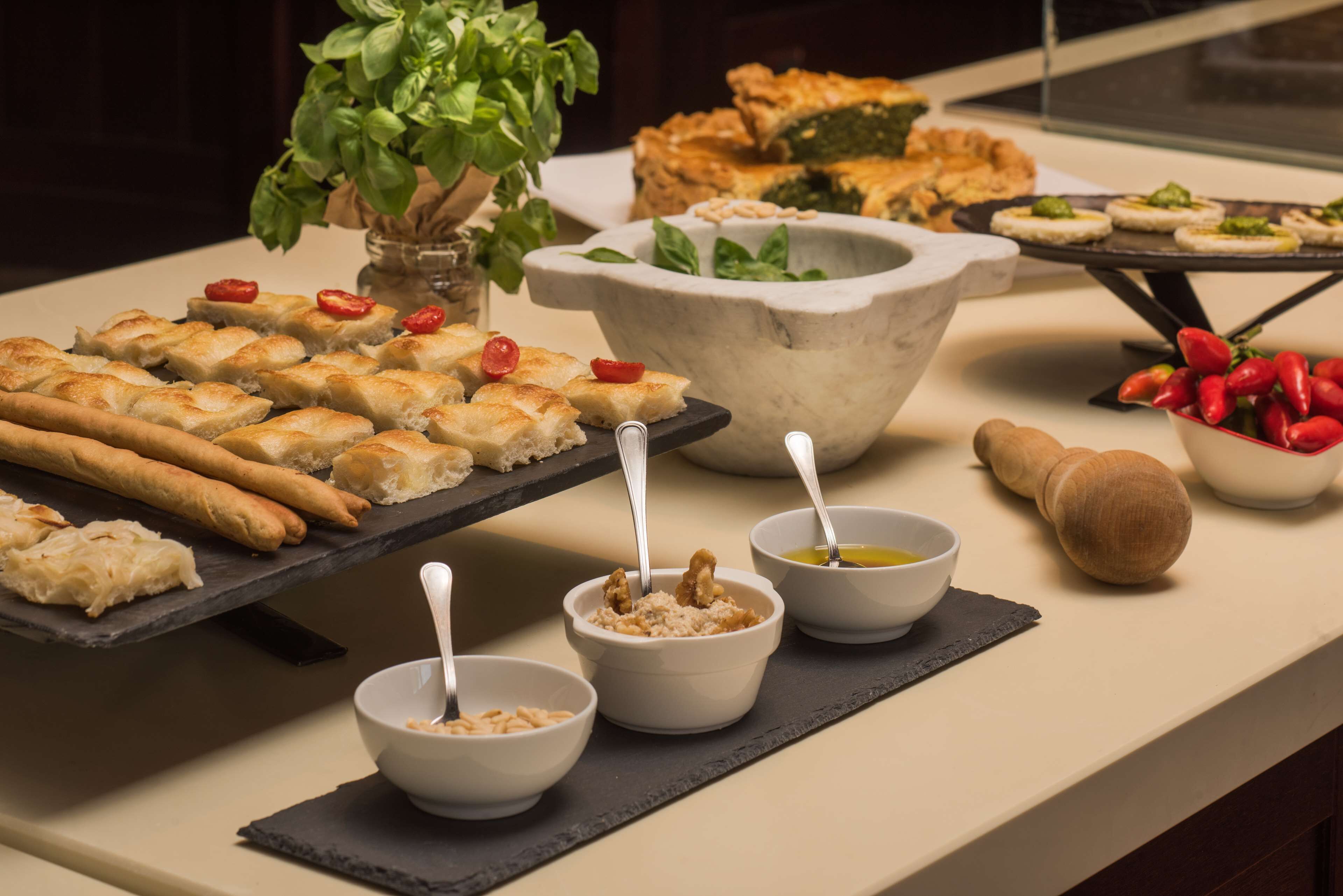 A buffet table with various dishes, including bread, dips, and a large stone bowl.