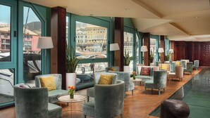 Un hall d’entrée spacieux avec de nombreux espaces de détente, de grandes fenêtres offrant une vue sur la ville et un décor moderne.