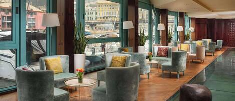 Un hall espacioso con varias zonas de estar, grandes ventanales con vistas a la ciudad y una decoración moderna.