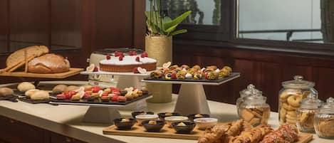 A buffet with various pastries, desserts, and bread on a counter.