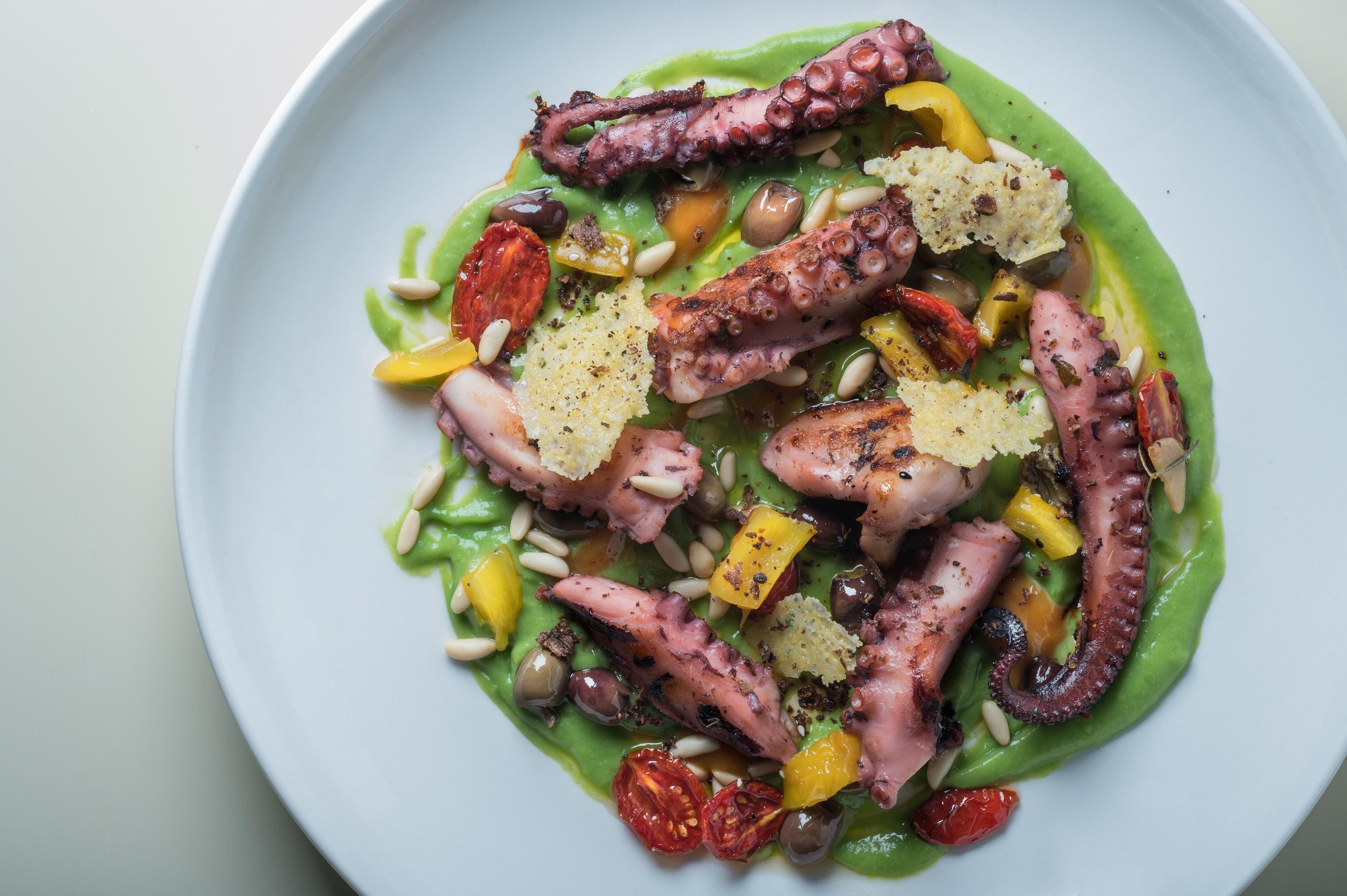 A plate of octopus salad with various vegetables and garnishes.