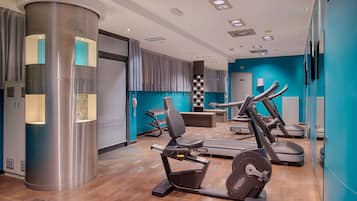 Een moderne sportschool met cardioapparatuur, een grote cilindervormige kolom en een blauwe accentmuur.