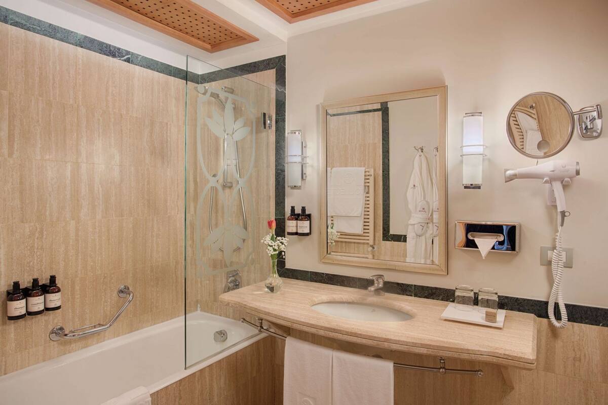 A modern bathroom with a glass shower enclosure, a double sink vanity, a hairdryer, and a mirror.