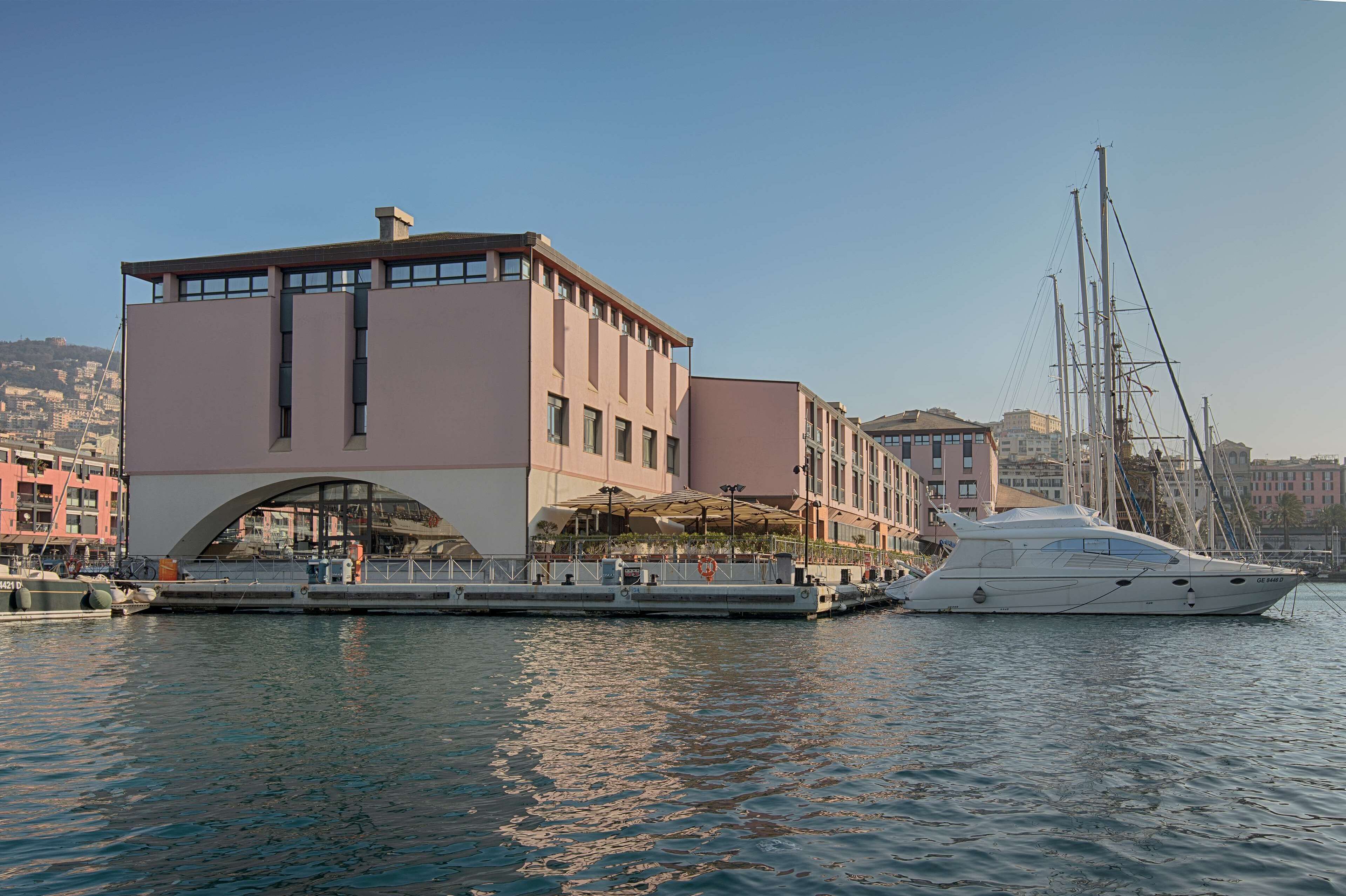A waterfront building with a large balcony and a yacht docked nearby.