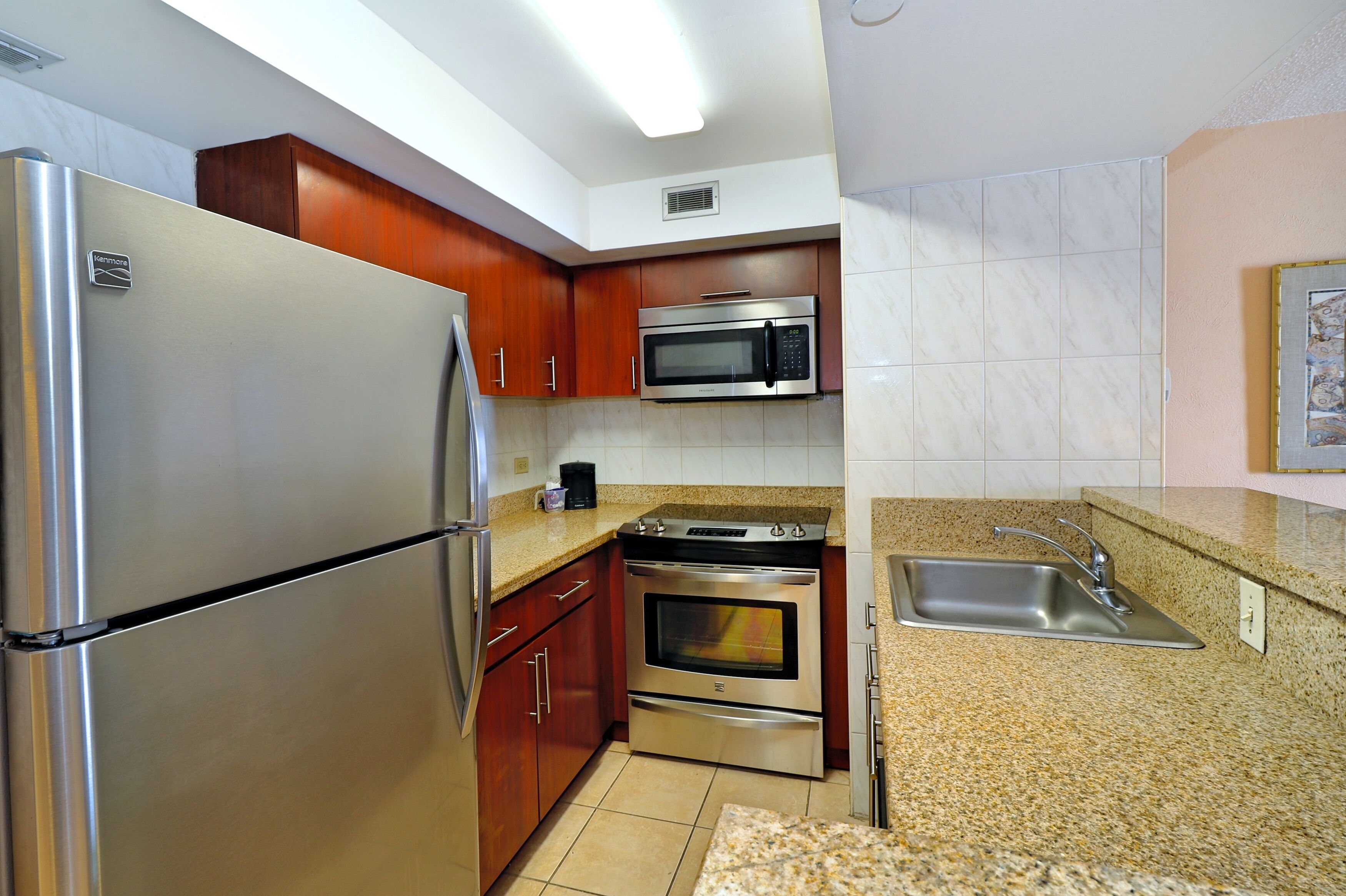 A kitchen with stainless steel appliances, wooden cabinets, granite countertops, and a built-in oven.