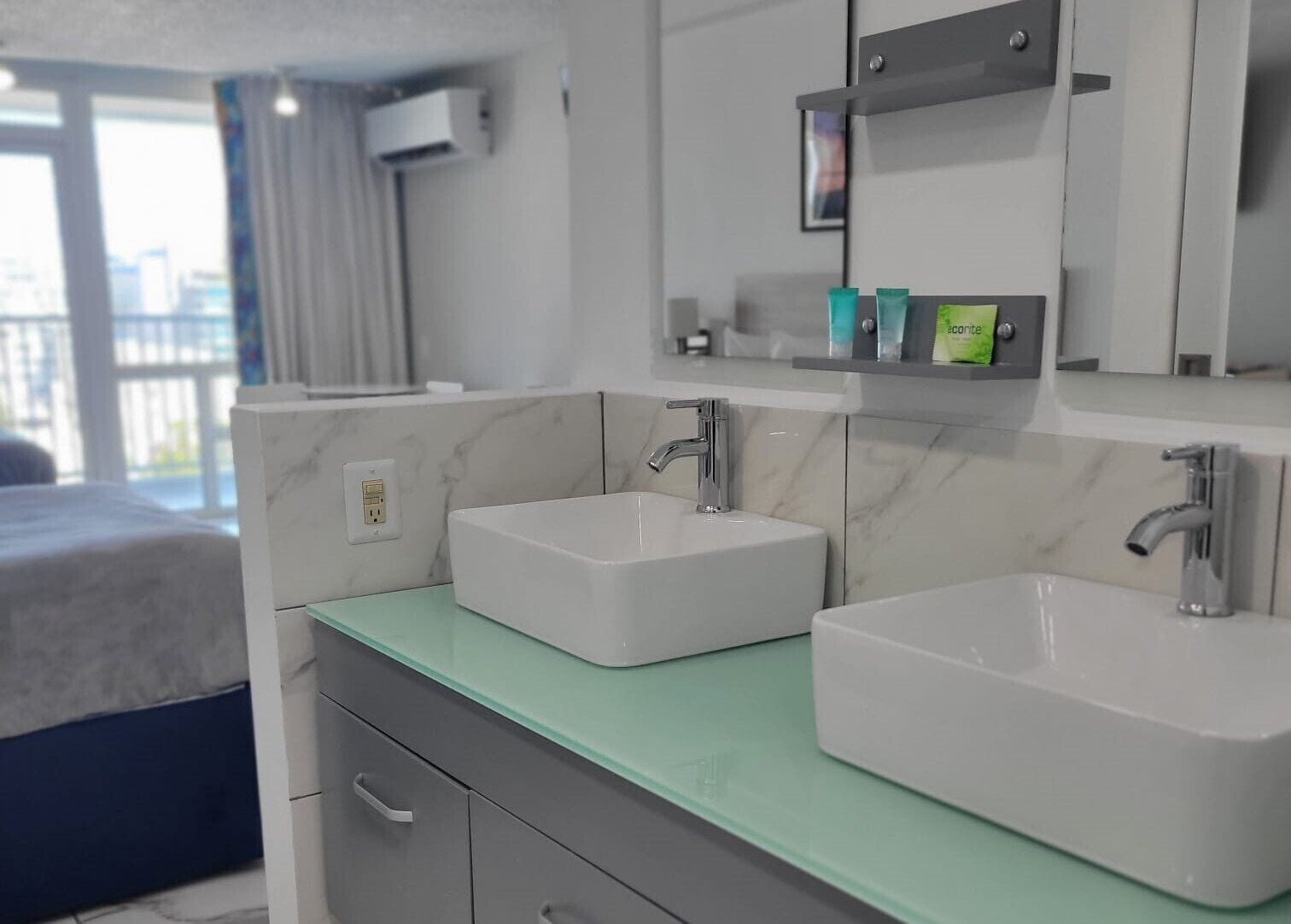 Un baño moderno con dos lavamanos, un espejo y un estante con artículos de aseo.