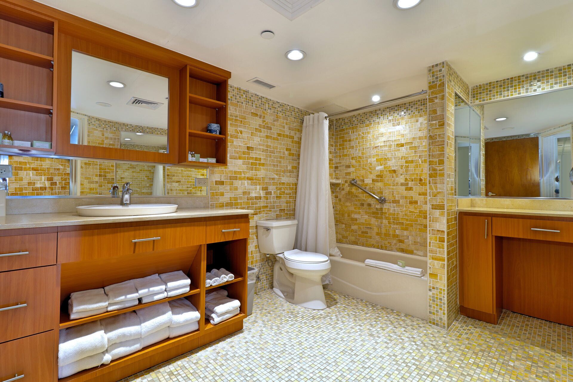 A bathroom with a wooden vanity, a sink, a toilet, and a bathtub.