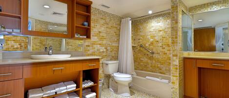 A bathroom with a wooden vanity, a sink, a toilet, and a bathtub.