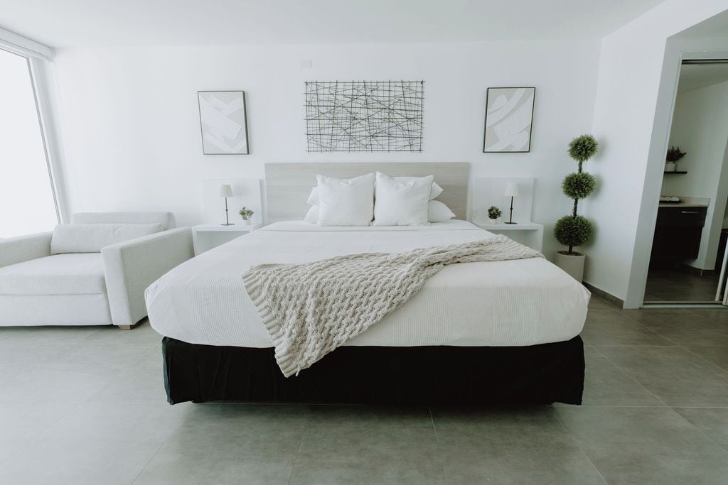 Une chambre à coucher moderne avec un grand lit, un canapé blanc et une petite table d’appoint.