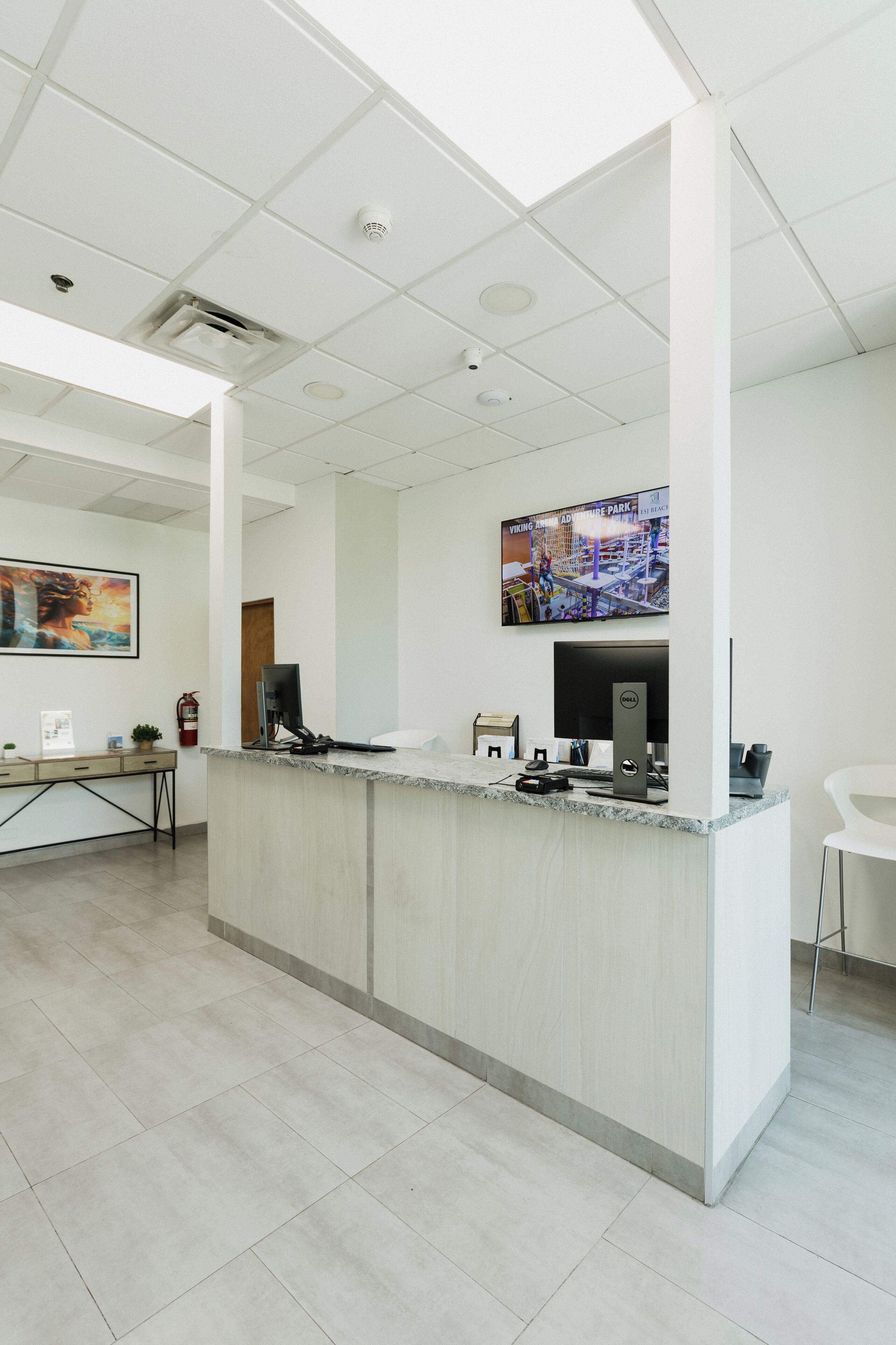 A reception area with a marble counter, a flat-screen TV, and a fire extinguisher.