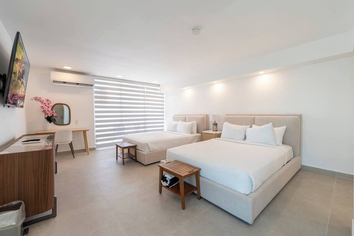 Ein Hotelzimmer mit einem großen Bett, einem Schreibtisch, einem Stuhl und einem kleinen Tisch.