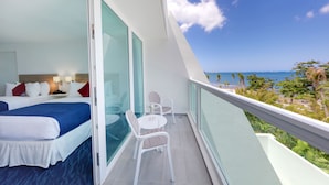 Un balcón con una cama, una mesa y sillas, con vista a la playa y el océano.