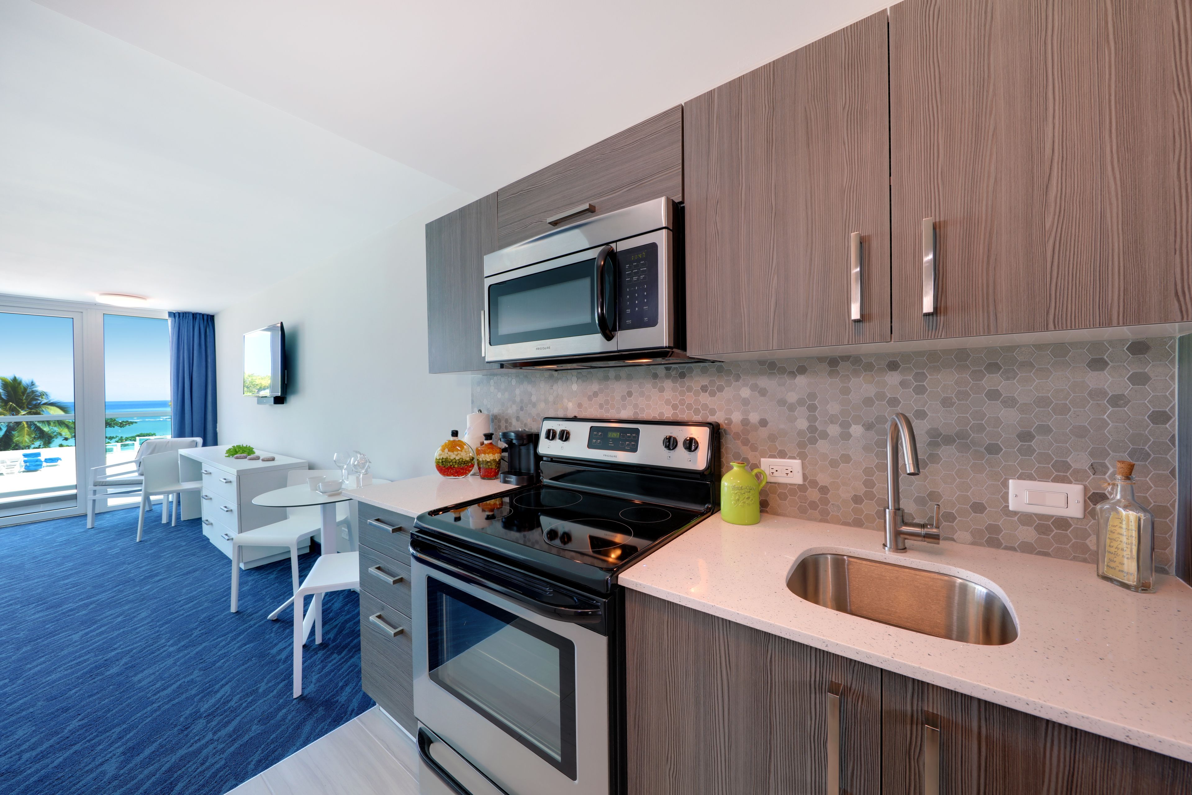 A modern kitchen with a microwave, stove, and sink. There is a dining area with a table and chairs.