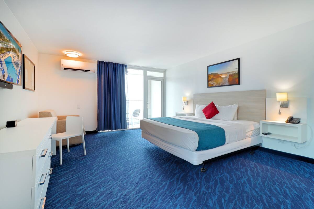 Habitación de hotel con cama, escritorio, silla y obras de arte en las paredes.