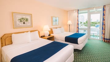 Quarto de hotel com duas camas, uma varanda com vista e paisagem urbana visível pela janela.