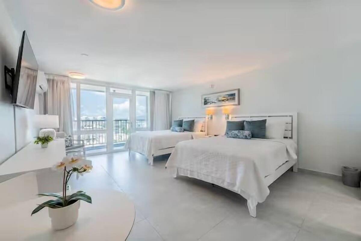Una habitación de hotel moderna con dos camas, un ventanal grande y un balcón.