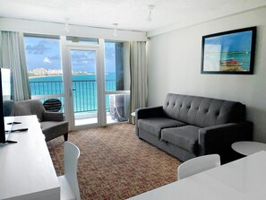 Enjoy ocean and city views from the large window in this stylish room, featuring a sofa, dining table, and flat-screen TV.