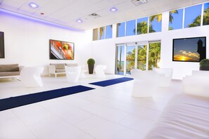 Relax in our spacious lobby with a central seating area, large windows offering views of palm trees and a vibrant artwork on the wall.