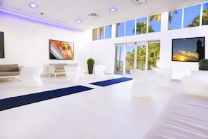 Relax in our spacious lobby with a central seating area, large windows offering views of palm trees and a vibrant artwork on the wall.