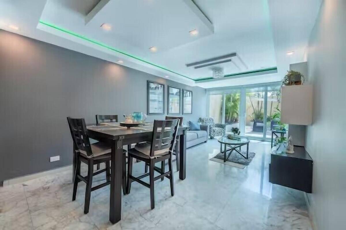 Un comedor moderno con una mesa y sillas de madera oscura, un sofá y una mesa de centro.
