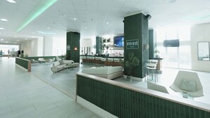 Un vestíbulo moderno con mostrador de recepción, zona de estar y bar.