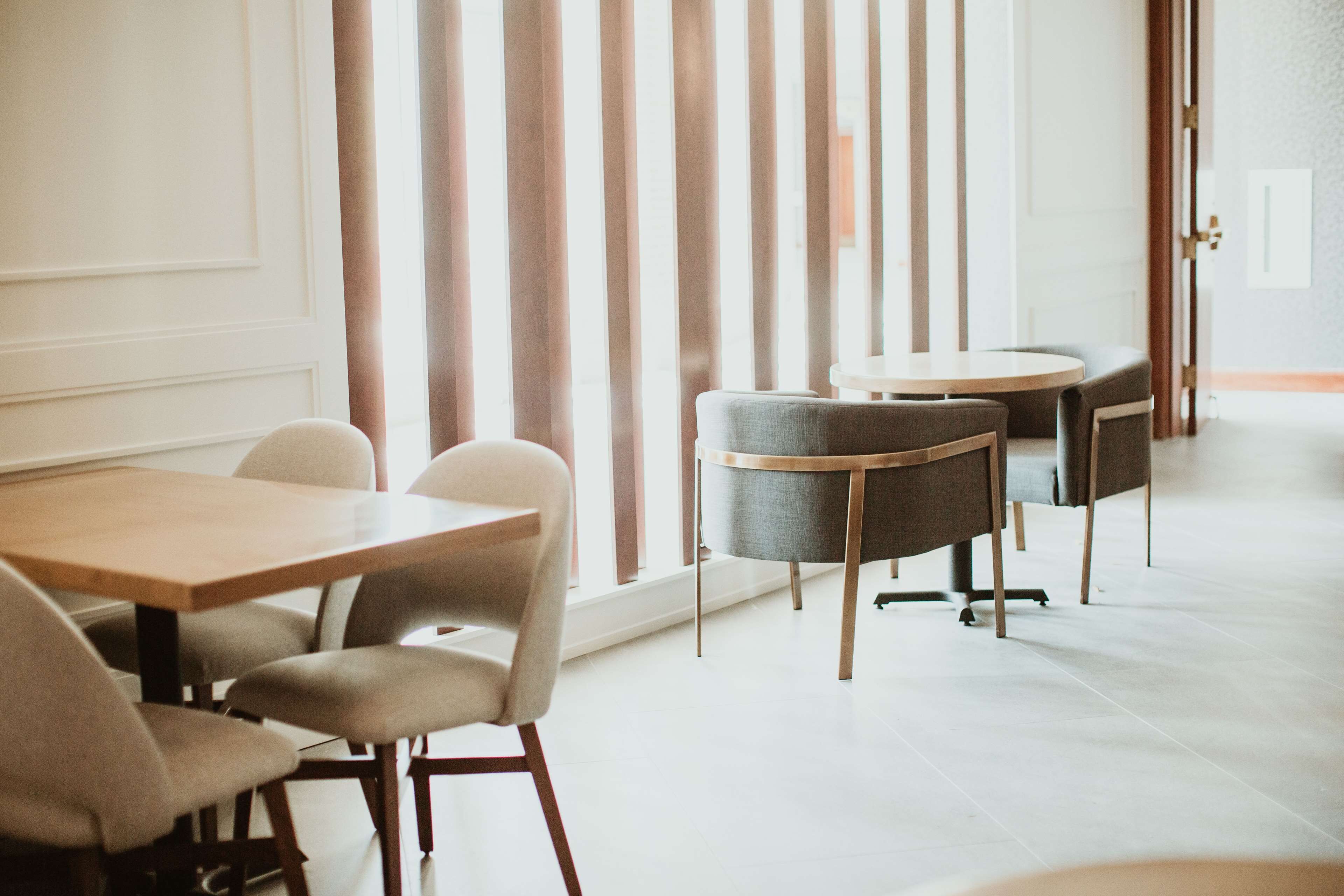 A modern dining area with a wooden table and chairs, a round table with a chair, and a striped partition.