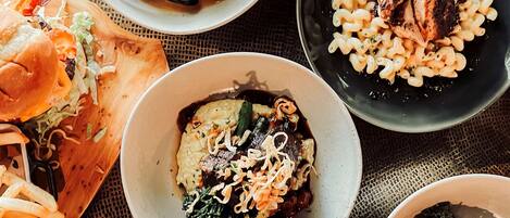 A variety of dishes including mussels, pasta, and a burger, arranged on a table.