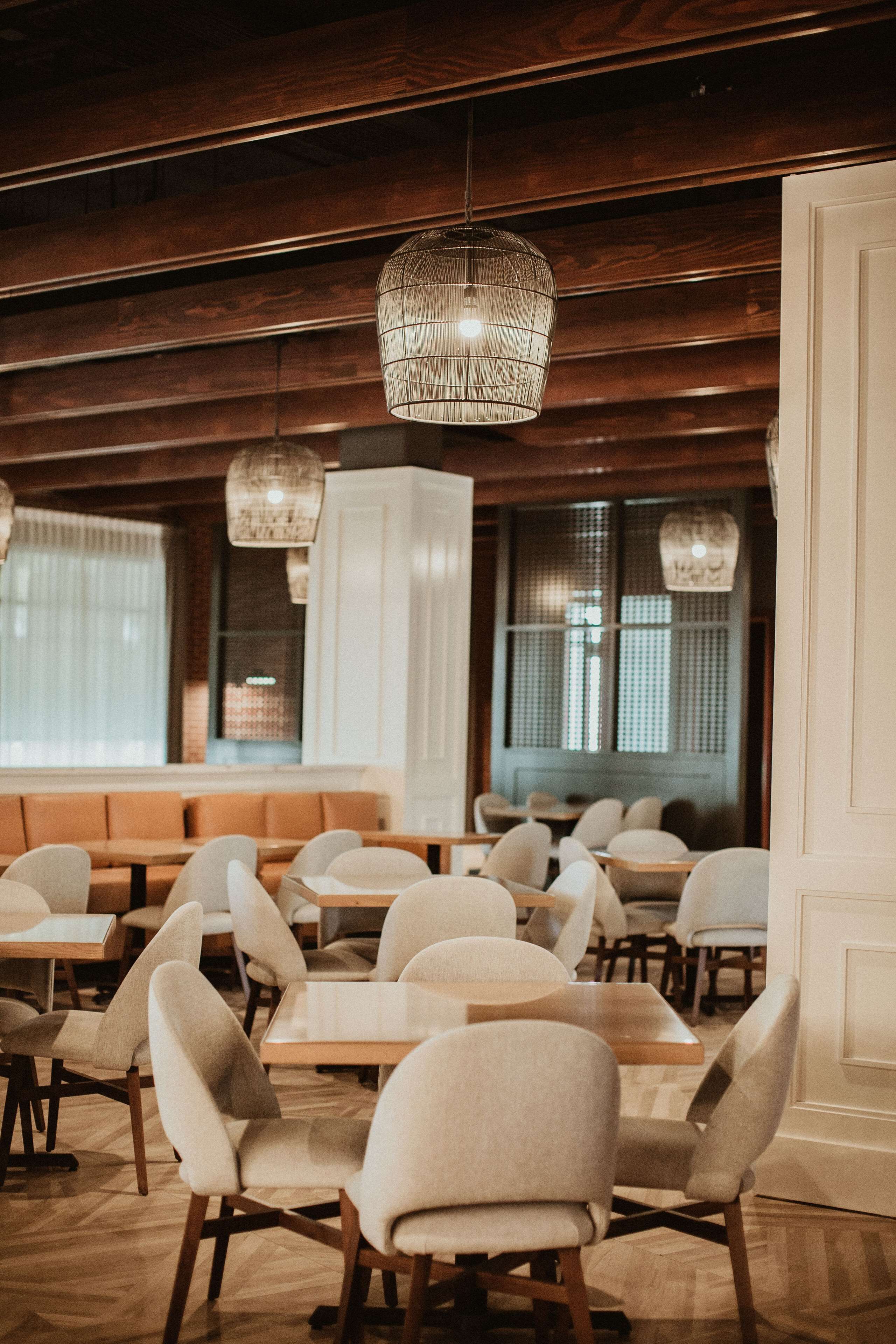 A restaurant interior with wooden paneling, hanging pendant lights, and a variety of seating arrangements including tables and booths.