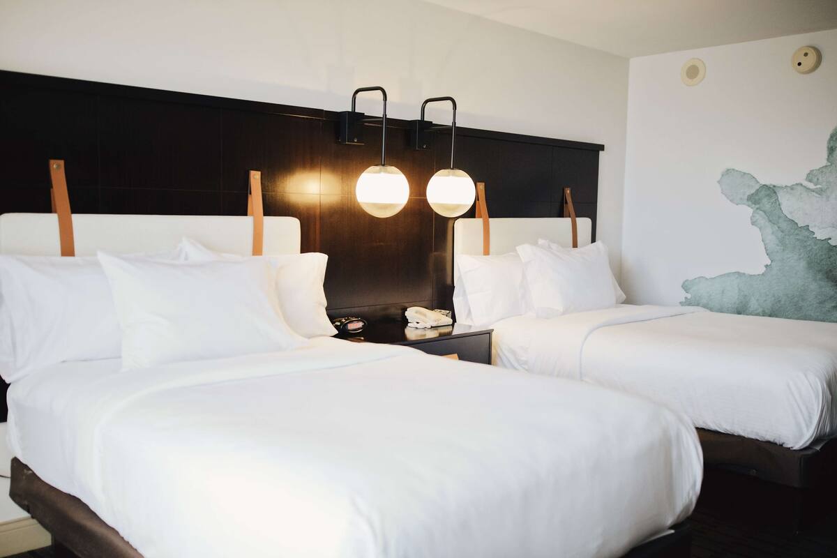 A hotel room with two beds, a dark headboard, and a wall map.